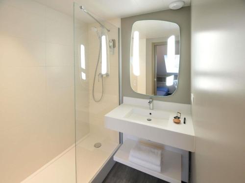 a bathroom with a sink and a shower with a mirror at ibis Nantes Saint Herblain in Saint-Herblain