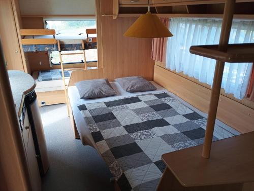 a small bedroom with a bed with a checkered floor at Karavan u přehrady in Prostějov