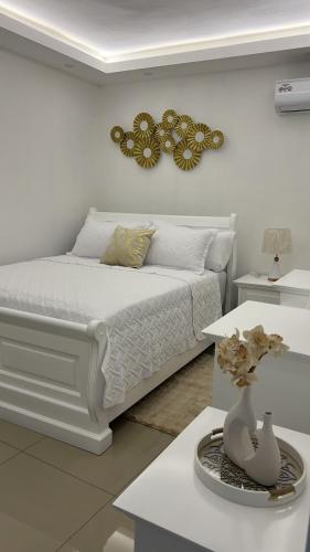 a white bedroom with a bed and a mirror on the wall at Los Alcarrizos Puente Blanco Urban Oasis ubicado en la calle 22 numero 98 los alcarrizos in Santo Domingo