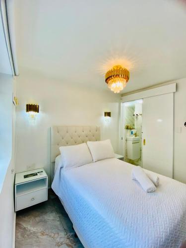 a white bedroom with a large bed and a chandelier at Hospedaje El Buen Descanso in Salento