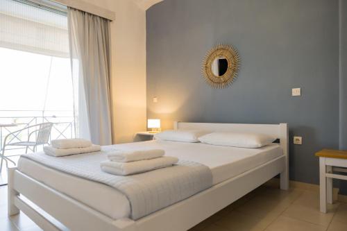 a bedroom with a bed with white sheets and a mirror at Μπλε Rooms & Apartments in Chiliadou