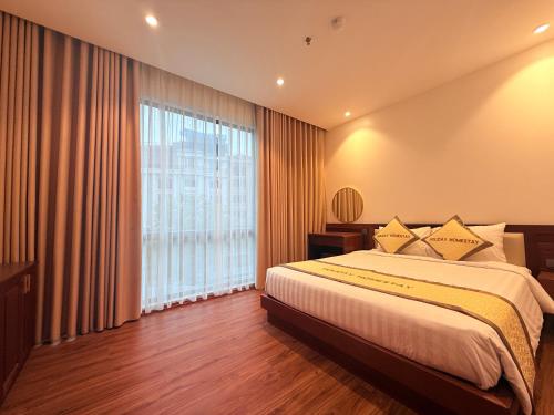 a bedroom with a large bed and a large window at Mer Suites Ha Long in Ha Long