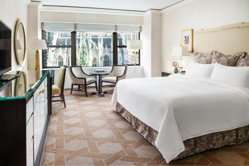 a bedroom with a large white bed and a dining room at Lotte New York Palace in New York