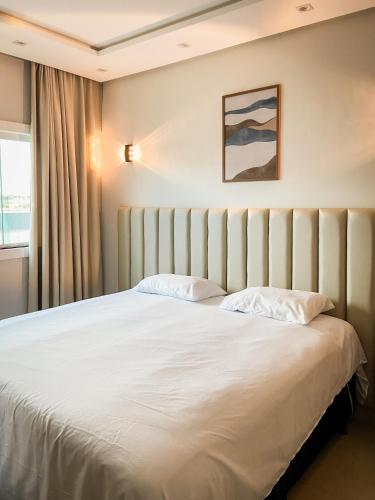 a bedroom with a large white bed with a window at Pousada Acessus Executivo - Cozinha e Lavanderia in Anápolis