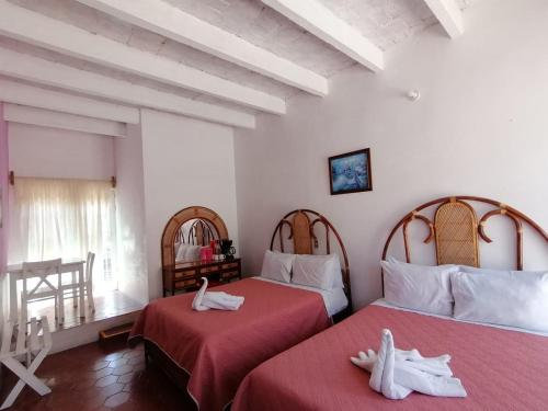 two beds in a room with red sheets at Hotel Elohim Tequis in Tequisquiapan