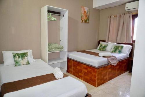 a room with two beds and a mirror at Hotel Lua y Origenes Santa Marta in Santa Marta