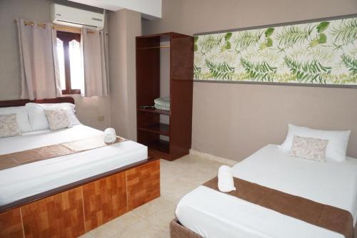 a bedroom with two beds and a wall mural at Hotel Lua y Origenes Santa Marta in Santa Marta