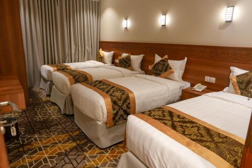 a hotel room with three beds in a room at فندق بالم بوتيك مكة in Az Zahrāʼ