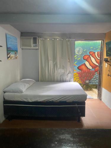a bed in a room with a painting on the wall at Pouso do caiçara suíte fundo do mar in Paraty