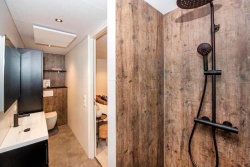 a bathroom with a shower with a wooden wall at Forest Cube 4 persons #706 in Maasbree