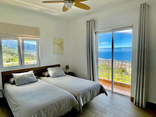 a bedroom with two beds and a large window at Sea view avocado Finca Ten Days in La Orotava