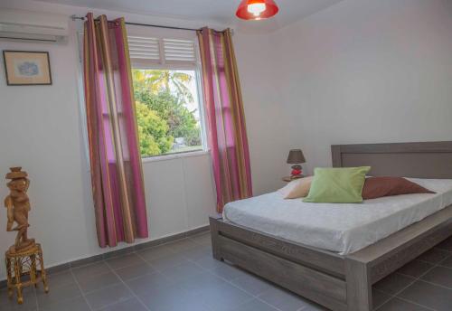 a bedroom with a bed and a window at Villa Joland in Sainte-Anne