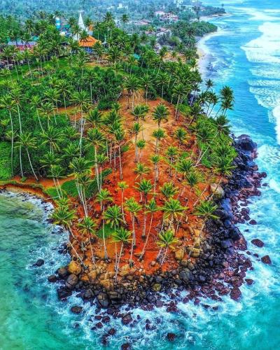 an island in the ocean with palm trees and water at Nisansala Villa in Matara
