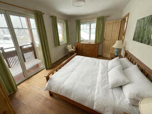 a bedroom with a bed with white sheets and windows at Landhaus Alpenblick Tauplitz in Tauplitz