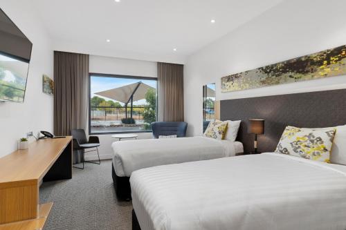 a hotel room with two beds and a desk at Quality Hotel Rules Club Wagga in Wagga Wagga