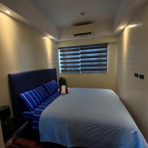 a bedroom with a large bed and a blue couch at RKJ condotel 2BR in Cupang