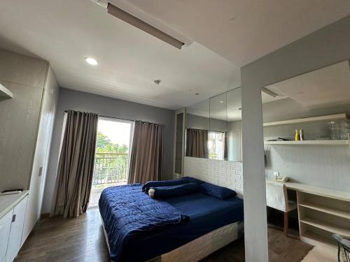 a bedroom with a blue bed and a large window at Studentpark apartment by RD in Yogyakarta