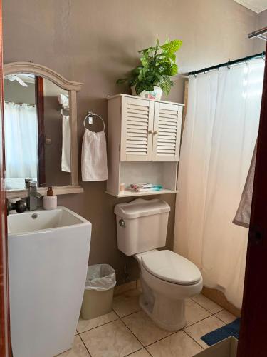 a bathroom with a toilet and a sink and a mirror at Hospedaje Ejecutivo Toronjal II in La Ceiba