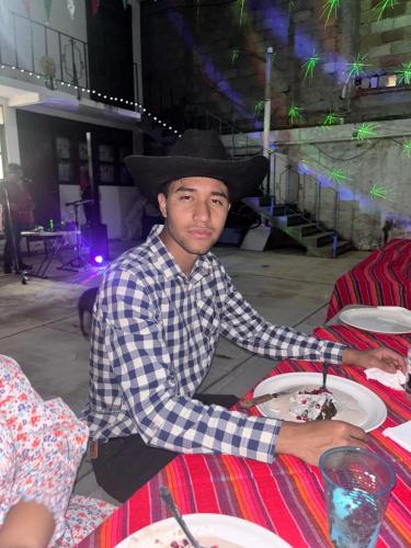 a man wearing a cowboy hat sitting at a table with a plate of food at Quinta Kendriel in Tezoyuca