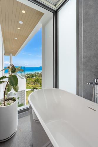 a white bath tub in a room with a large window at Mee Kham Sook Luxury Villa in Nathon Bay