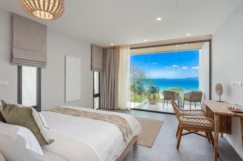 a bedroom with a bed and a desk and a view of the ocean at Mee Kham Sook Luxury Villa in Nathon Bay