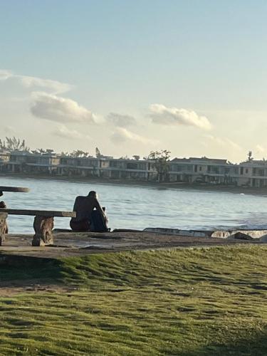 a person sitting on a bench next to the water at Serenity Escape, Cozy Stay w Secure Parking in Runaway Bay