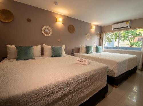 two beds sitting in a room with a window at Hotel Bocagrande Cartagena in Cartagena de Indias