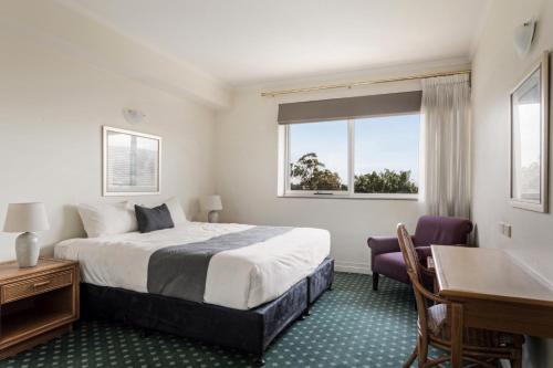 a hotel room with a bed and a desk and window at Mary MacKillop Spirituality Centre Baulkham Hills in Baulkham Hills