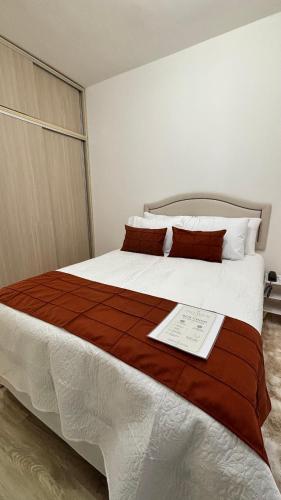 a bedroom with a large white bed with red pillows at Palladium Refúgio - 500 metros da Praia, Perto do Shopping, Wi-Fi, Piscina e Garagem in São Vicente