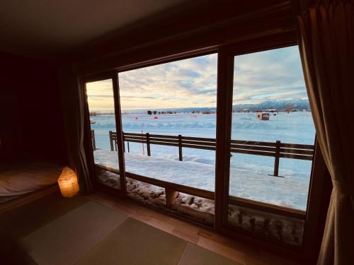 a room with a window looking out at a snow covered field at Hokkaido Zen Cabin in Bibai