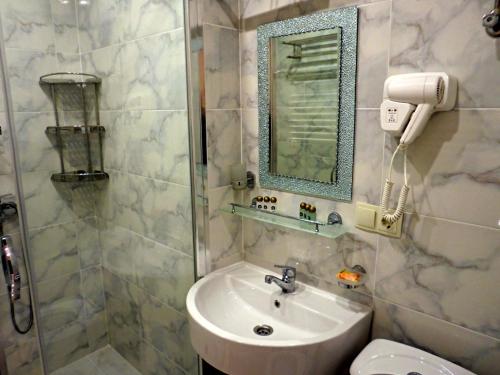 a bathroom with a sink and a mirror and a toilet at Sea View Rock Hotel in Batumi