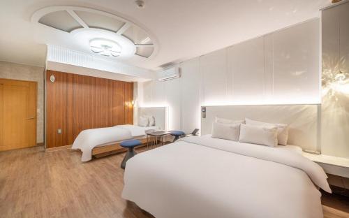 a bedroom with a large white bed and a couch at Andong Win Hotel in Hoam-dong