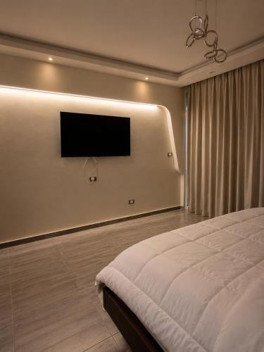 a bedroom with a bed and a flat screen tv at Pyramids Gardens 2bedroom apartment in ‘Ezbet `Abd el-Ḥamîd