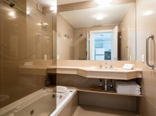 a bathroom with a sink and a tub and a mirror at Green Park Departamentos Exclusivos in Punta del Este
