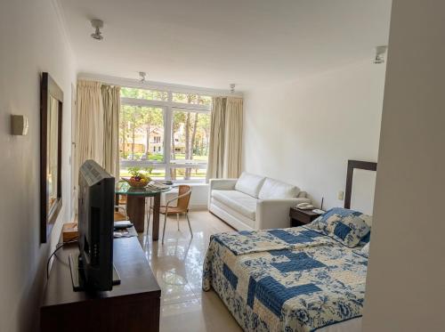 a hotel room with a bed and a couch and a television at Green Park Departamentos Exclusivos in Punta del Este