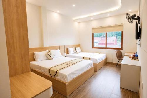 a hotel room with two beds and a desk at TherHouse in Mộc Châu