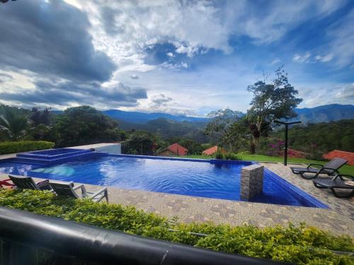 a swimming pool with chairs and mountains in the background at Finca Villa Julia - Cabañas in La Vega