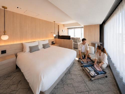 two people sitting on a large bed in a room at HOTEL THE LEBEN OSAKA in Osaka