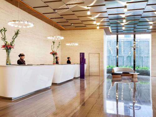 a lobby with people sitting at a reception counter at Grand Mercure Jakarta Harmoni in Jakarta