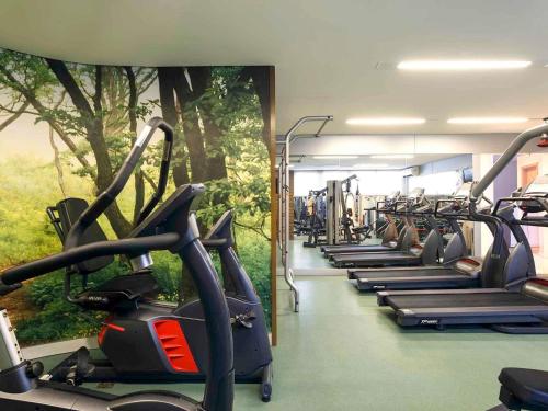 a gym with a row of treadmills and a tree mural at Mercure Salvador Pituba in Salvador