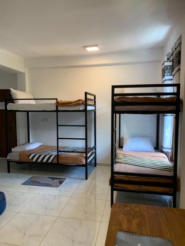 two bunk beds in a room with a table at Noname Hostel ella in Ella