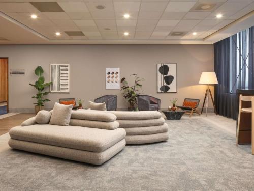 a living room with two white couches in a room at Mercure Hotel Amersfoort Centre in Amersfoort