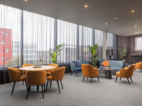 a large room with a table and chairs and windows at Mercure Hotel Amersfoort Centre in Amersfoort