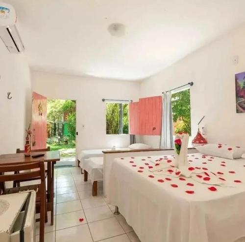 a bedroom with two beds and a desk and two windows at Cajibá Imbassai in Imbassai