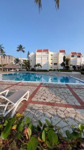 a swimming pool with two chairs and a building at my house on the upper beach in Villas del Mar