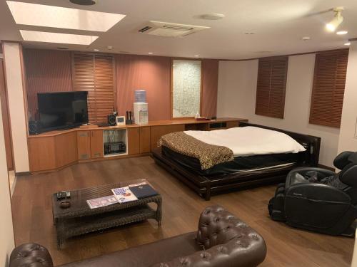 a bedroom with a bed and a tv and a couch at Rplus八千代 in Chiba