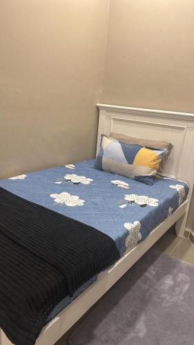 a bed with a blue comforter and pillows on it at Yueeda Homestay in Jertih