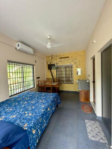 a bedroom with a bed and a desk and windows at Fruits Garden Resort in Kotamangalam