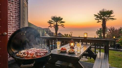 a grill with food on a table on a balcony at geoje yeoul pet-friendly pension in Yŏch'a