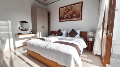 a bedroom with a large bed with white sheets at Villa Kasuri Bali in Blahbatu